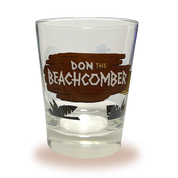 A Mai Tai glass with Donn Beach leaning on a rum barrel on a beach that says “rum ship to Donn Beach” on one side and the Don the Beachcomber Logo on the other side.